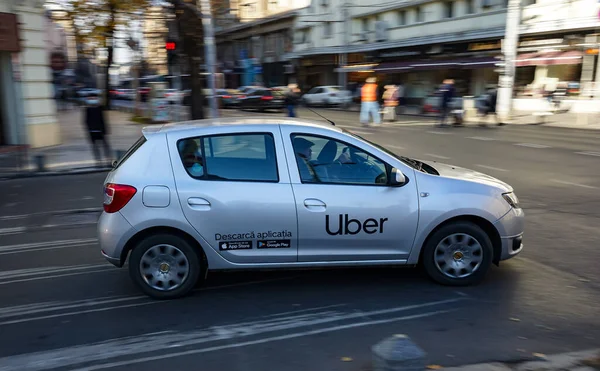 An Uber logo branded car is seen in traffic on a street