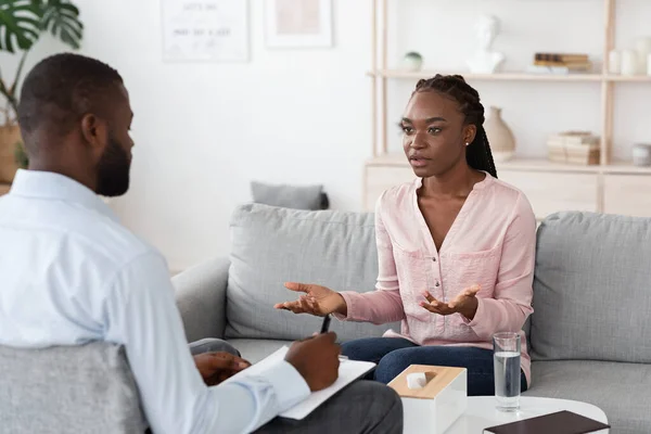 Desperate woman talking to professional psychologist at therapy session in his office for her mental health wellness